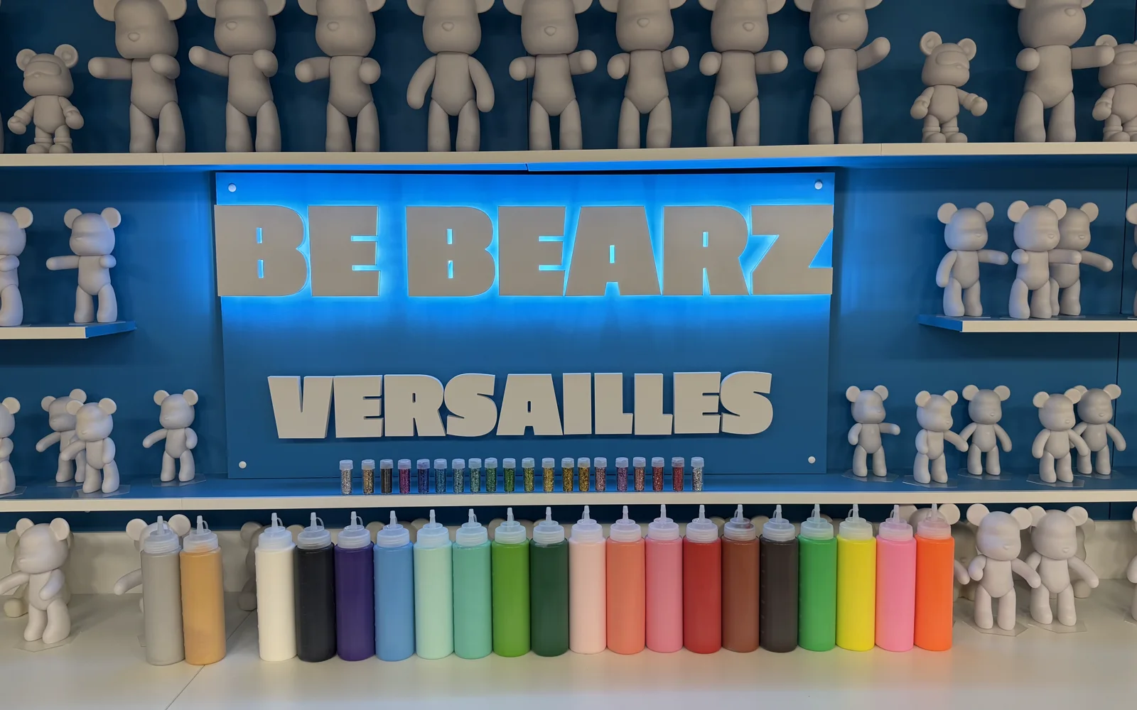 L'enseigne lumineuse BE BEARZ Versailles, le mur d'oursons et les flacons de peinture